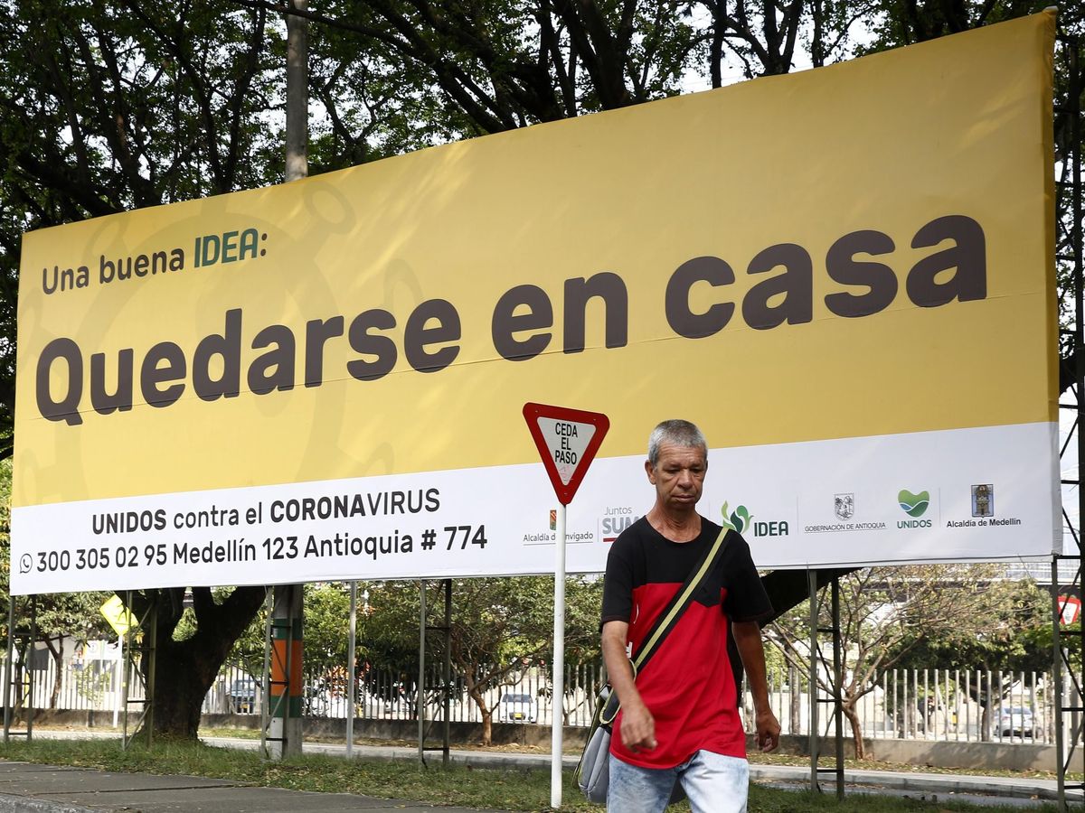 Foto: Un hombre camina frente a una publicidad que invita a la ciudadanía a quedarse en casa, como medida contra el coronavirus, este lunes, en Medellín (Colombia). (EFE)