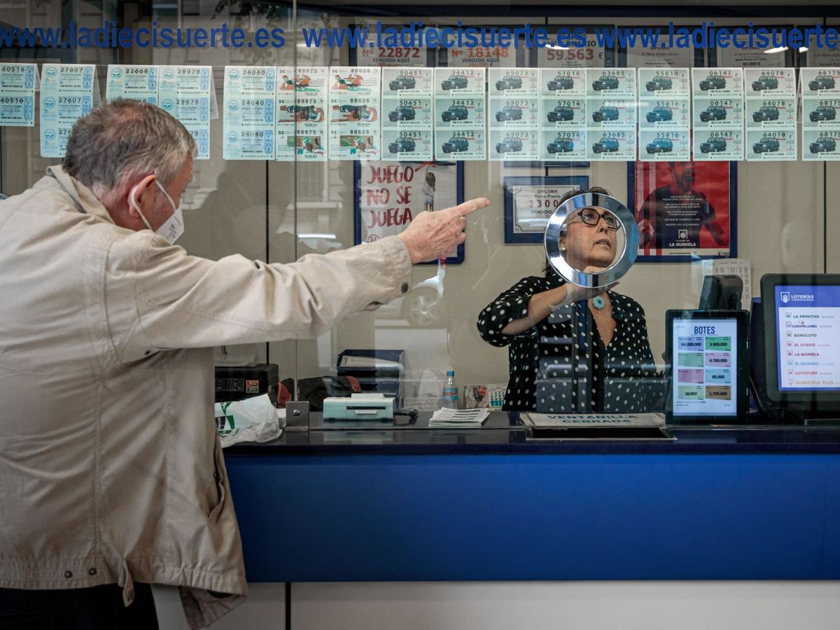 Foto: Un cliente busca un número de la lotería de Navidad en una administración. (EFE)