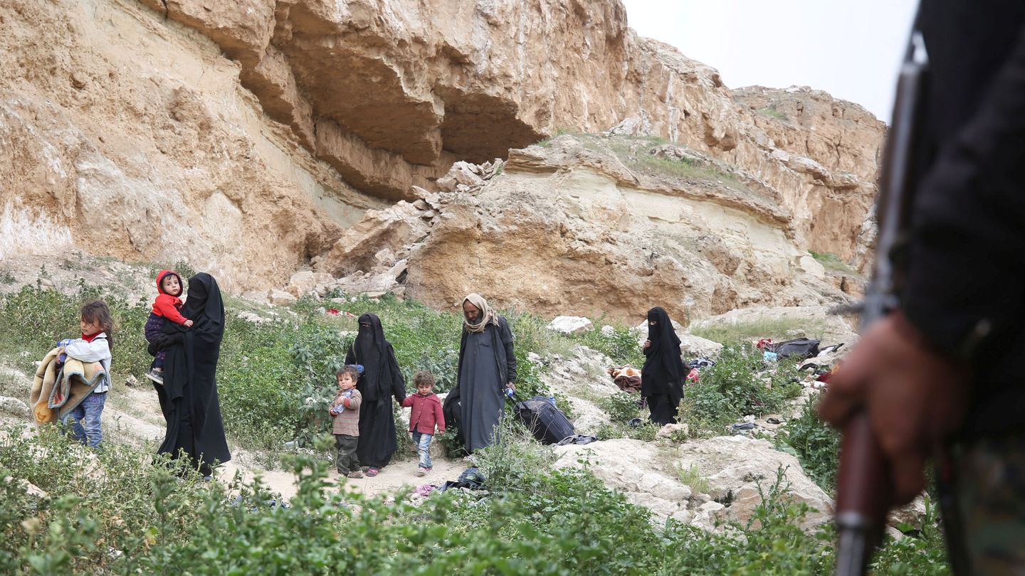 Un combatiente del Estado Islámico junto a varias mujeres y niños se entrega a los kurdos en Baghouz, Siria. (Reuters)