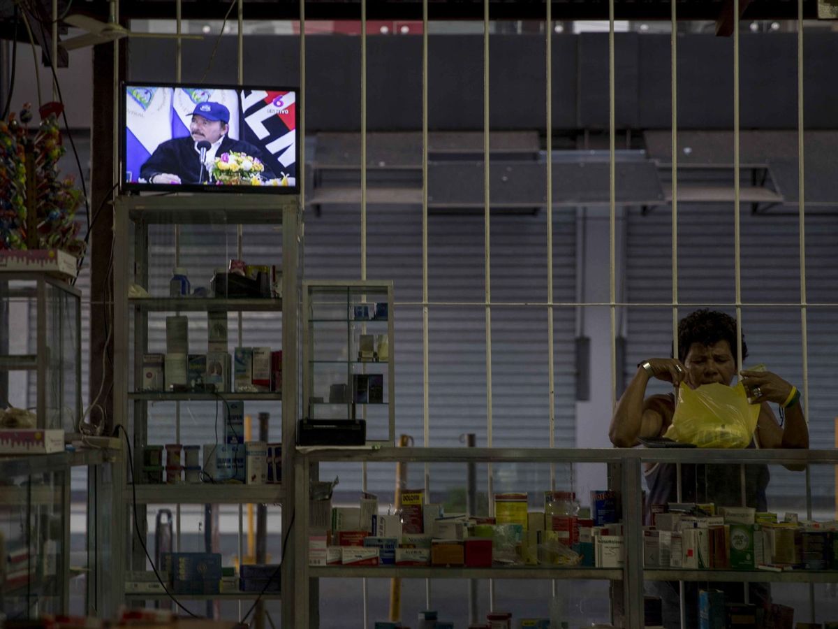 Foto: Una mujer realiza compras en una tienda de abarrotes mientras en la pantalla de un televisor aparece el presidente de Nicaragua (EFE)