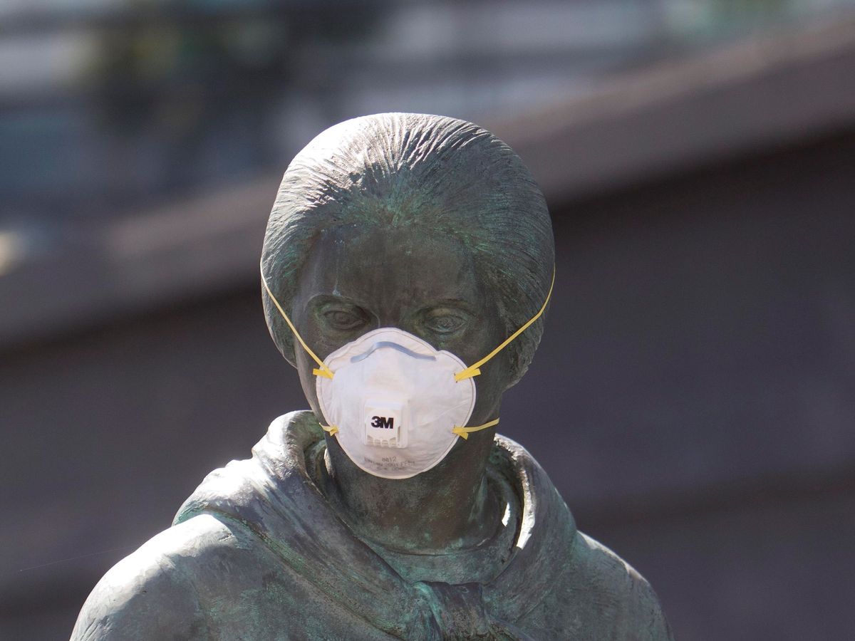 Foto: Una de las esculturas de la obra en honor a los emigrantes del puerto de Vigo aparece cubierta con una mascarilla. (EFE)