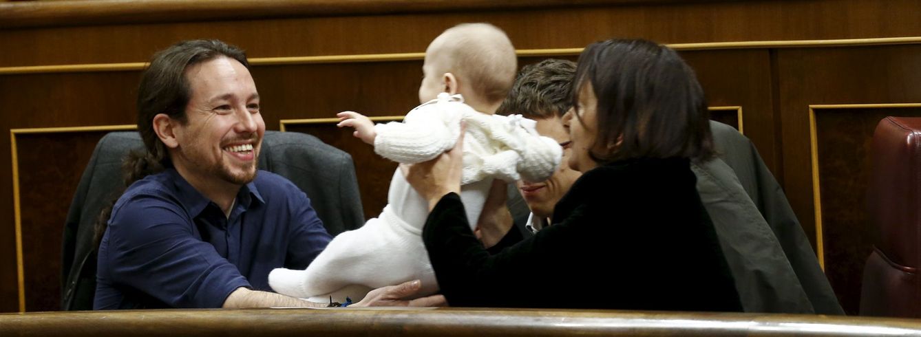 Bescansa le pasa su hijo a Pablo Iglesias desde su escaño durante un momento de la sesión. (Reuters)