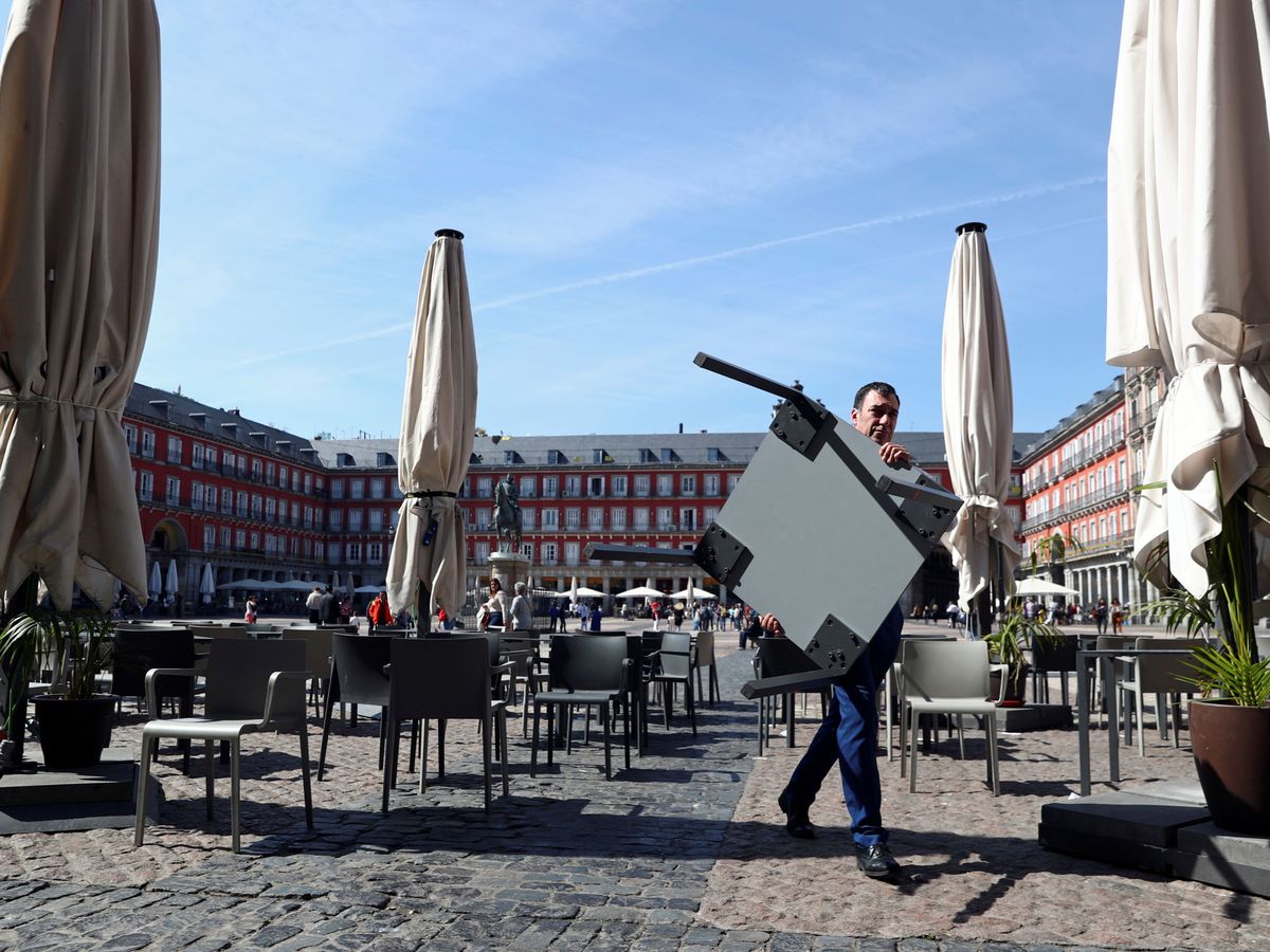 Foto: Un camarero retira las mesas de una terraza en la Plaza Mayor de Madrid tras la orden de cierre de bares. (EFE)
