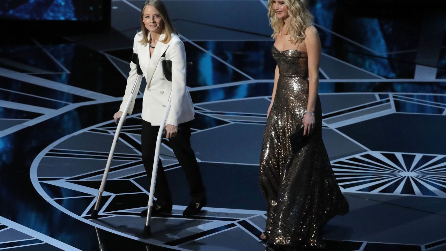 Jodie Foster en muletas junto a Jennifer Lawrence entregan el Oscar a la Mejor Actriz. (Reuters)