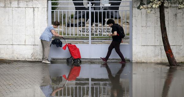 Foto: Dos personas intentan pasar por una zona inundada en la avenida de Pío XII, en Madrid, a causa de las fuertes lluvias y el granizo. (EFE)