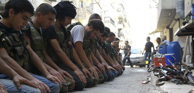 Combatientes del Ejército de Liberación sirio rezan en una calle de Alepo (Reuters).