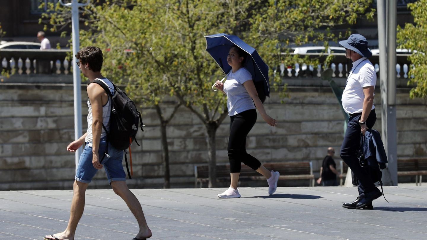 Turistas protegidos con sombrero o paraguas en Bilbao. (EFE)
