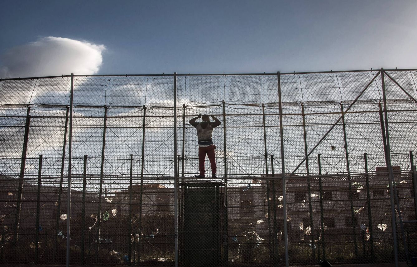 Foto: Un migrante subsahariano, en la valla de Melilla tras intentar entrar en territorio español. (Reuters)
