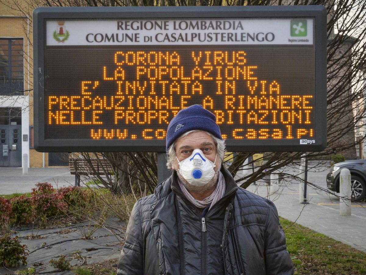 Foto: Un hombre con mascarilla posa ante un cartel que alerta del coronavirus en Casalpusterlengo. (EFE)