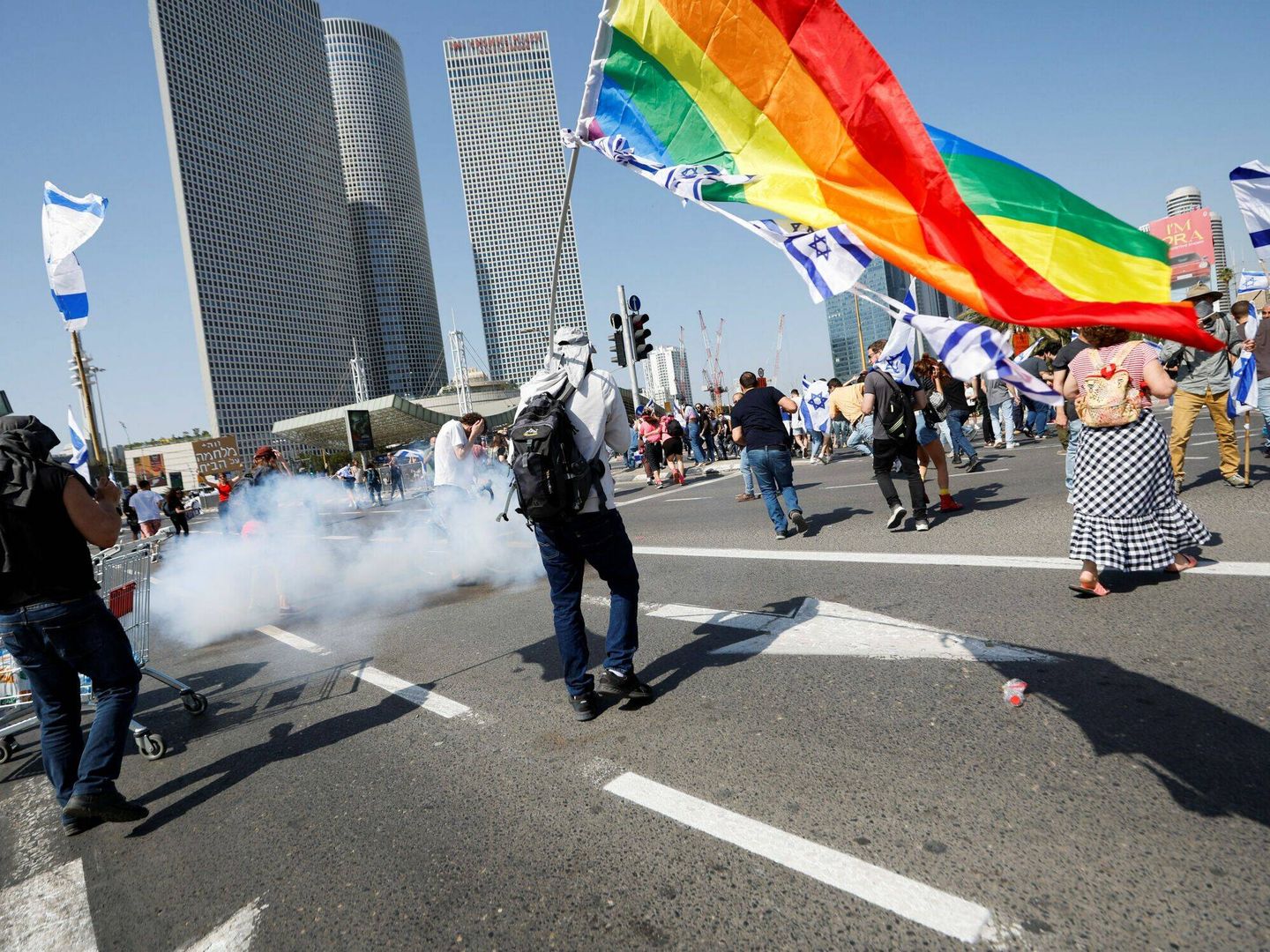 Un joven con una bandera LGTBI frente al gas lanzado por la Policía. (Reuters/Amir Cohen)