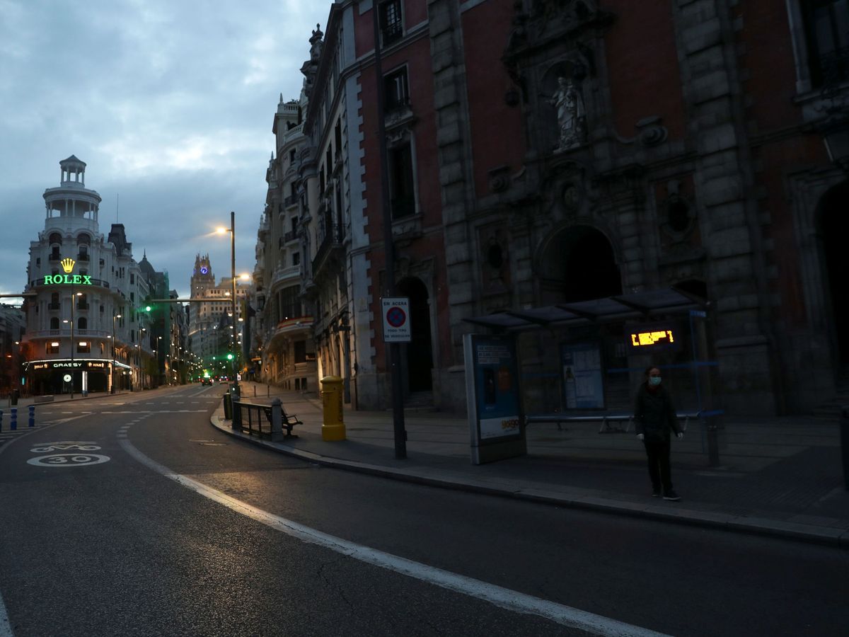 Foto: Una mujer espera al autobús en la calle Alcalá durante la epidemia. (Susana Vera / Reuters)