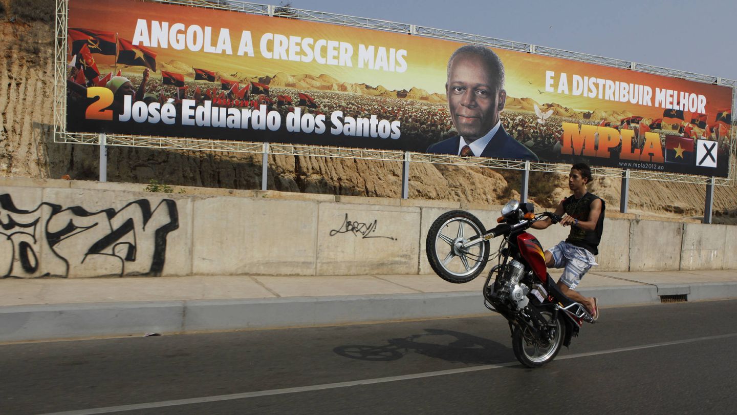 Un motociclista pasa delante de un poster de Dos Santos en Luanda, en 2012. (Reuters)