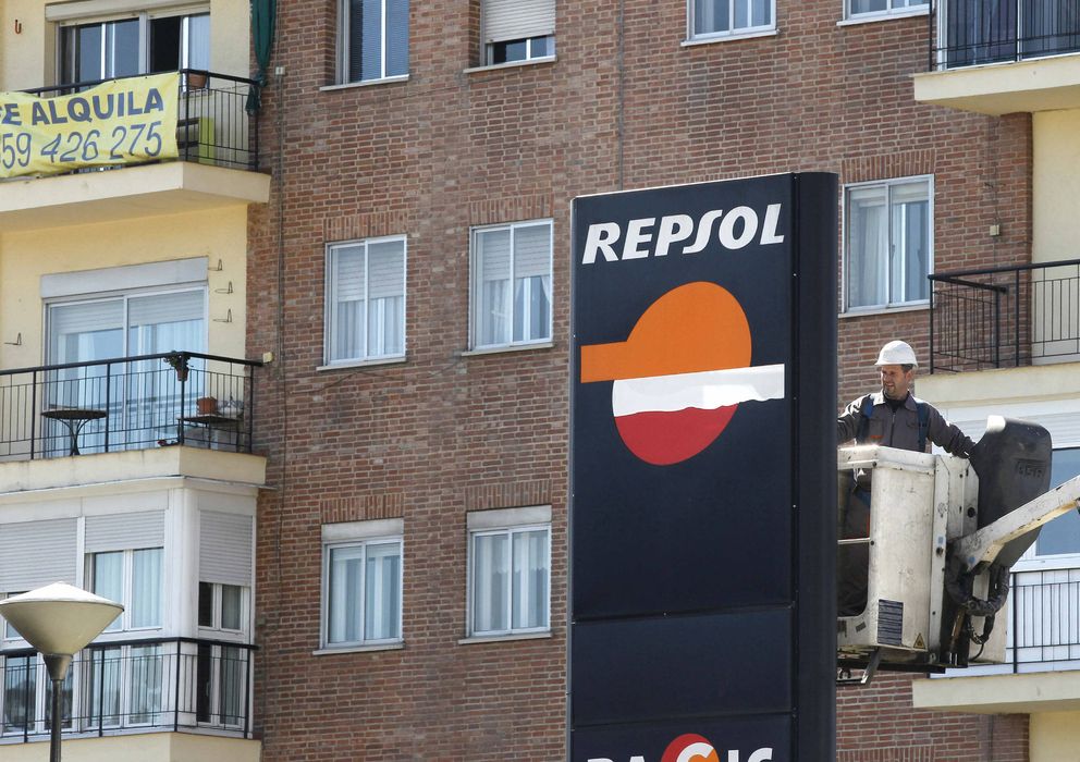 Foto: Un operario trabaja en un panel de Repsol en una gasolinera de Madrid. (EFE)