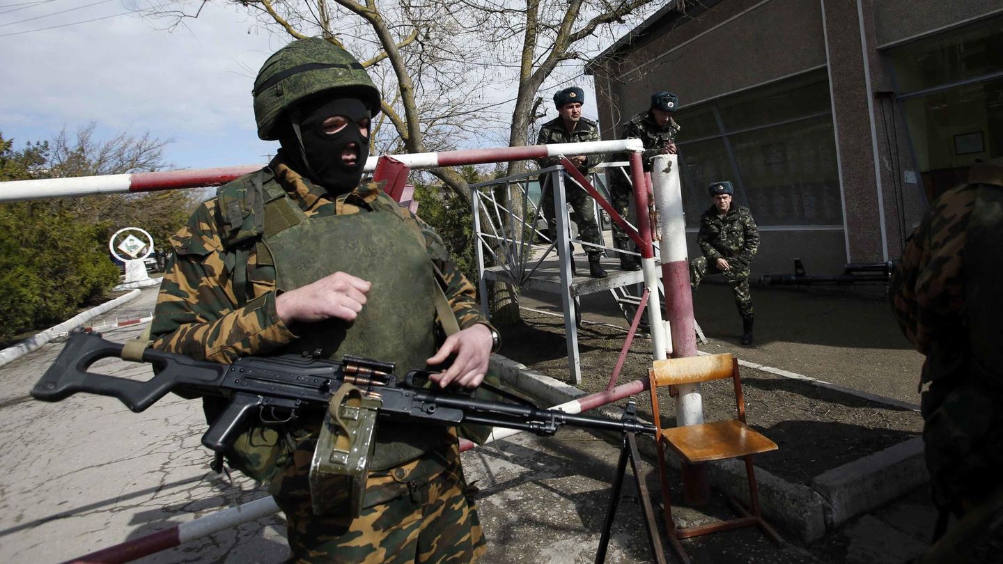 Soldados ucranianos observan a un militar ruso sin distintivos en la puerta de la base de Yevpatoria (Reuters).
