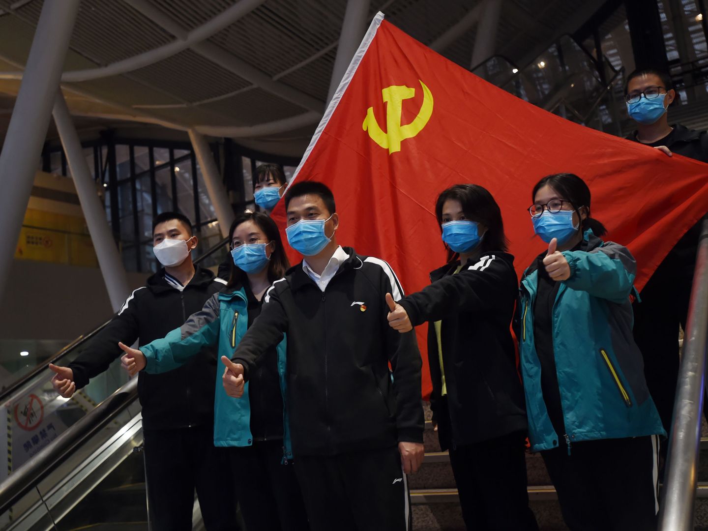 Varios médicos chinos posan con una bandera comunista detrás. (Reuters)