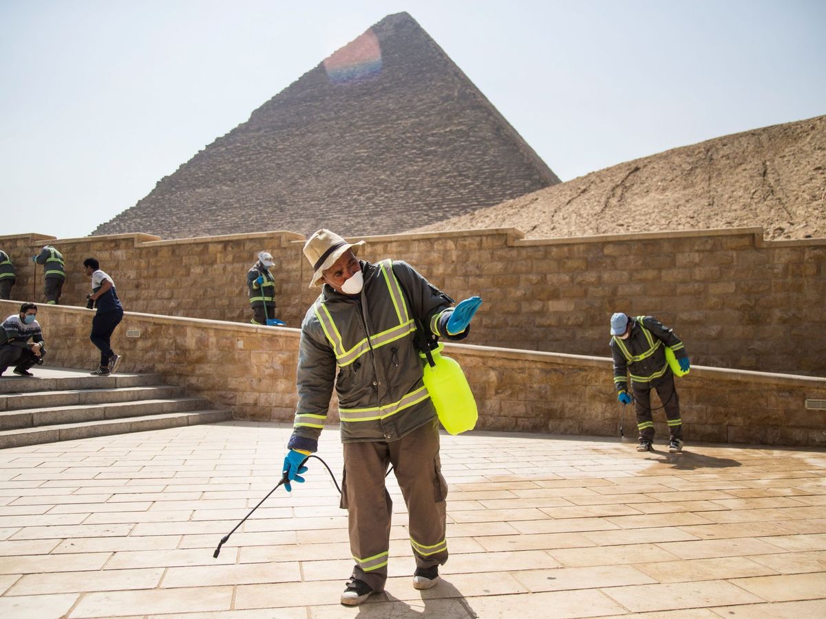 Foto: Varias personas desinfectan las inmediaciones de las pirámides de Guiza. (EFE) 