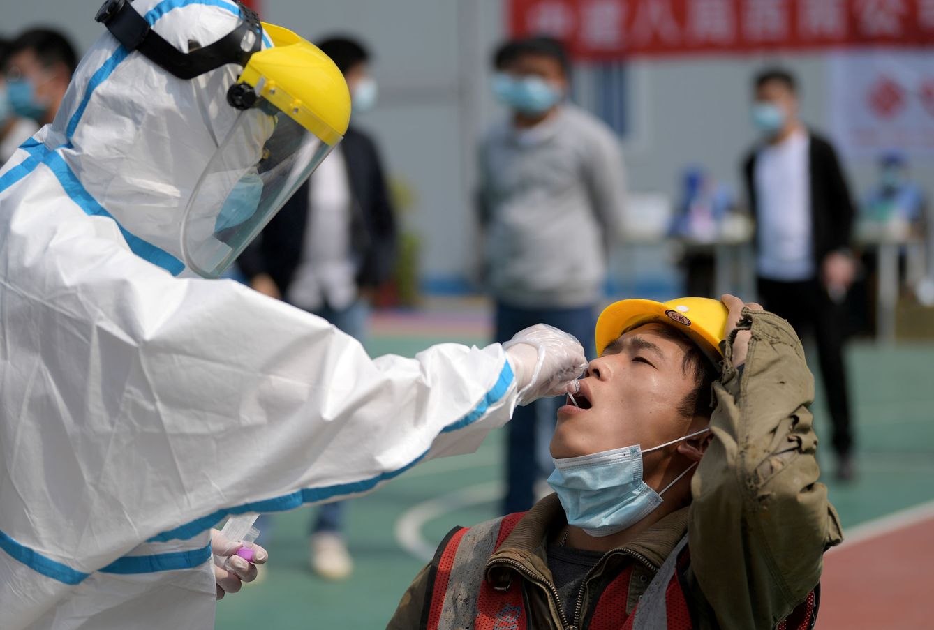 Un empleao sanitario le hace un test rápido de coronavirus a un trabajador chino en Wuhan. (Reuters)