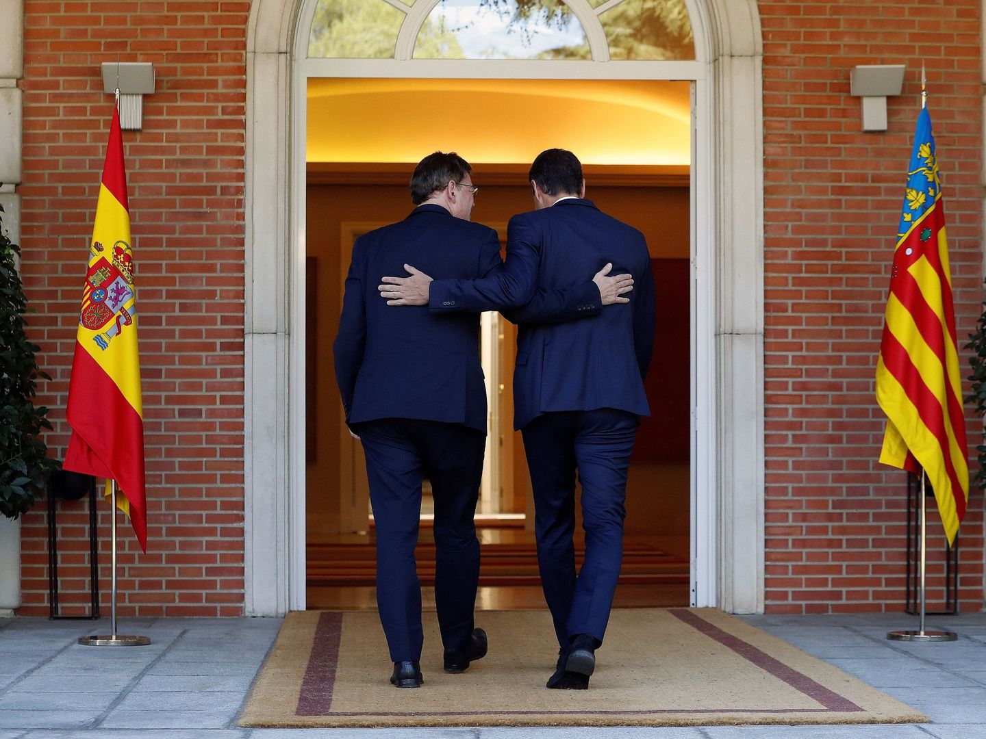Pedro Sánchez y Ximo Puig en Moncloa, con las banderas de España y de la Comunidad Valenciana a ambos lados de la puerta del edificio del Consejo de Ministros. (EFE)