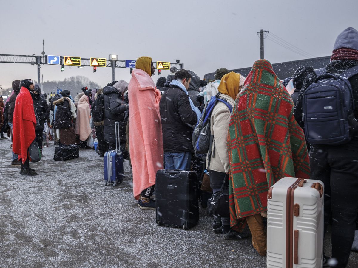 Foto: Varias personas procedentes de Ucrania esperan el autobús tras cruzar la frontera con Polonia en Medyka. (EFE/Biel Aliño)