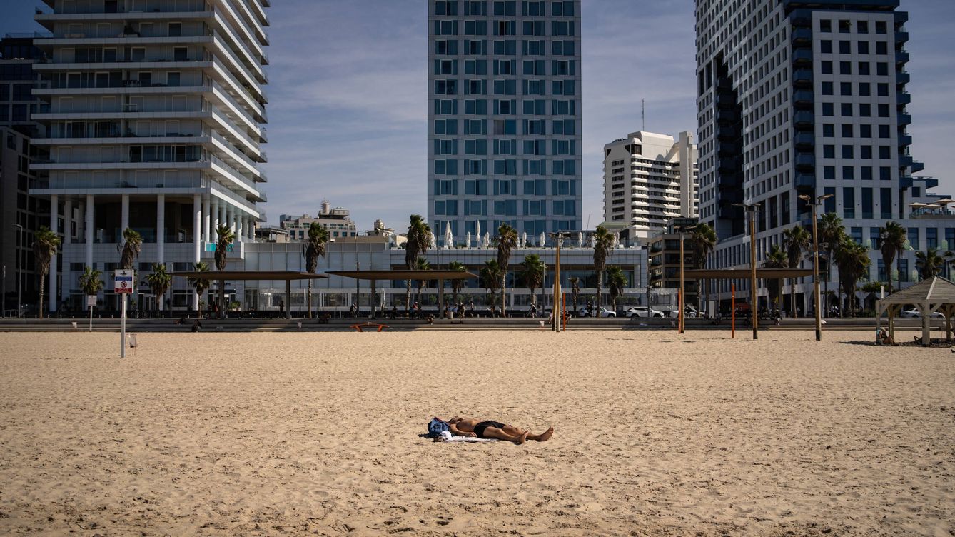 Foto: Un hombre toma el sol en la playa de Tel Aviv, mientras la guerra se recrudece en Gaza. (Fermín Torrano)