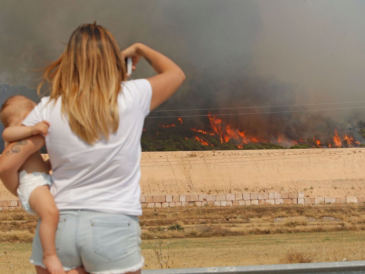 Foto: Una mujer observa el avance de las llamas del incendio forestal que se ha declarado entre las localidades alicantinas de Monóvar y La Romana (EFE)