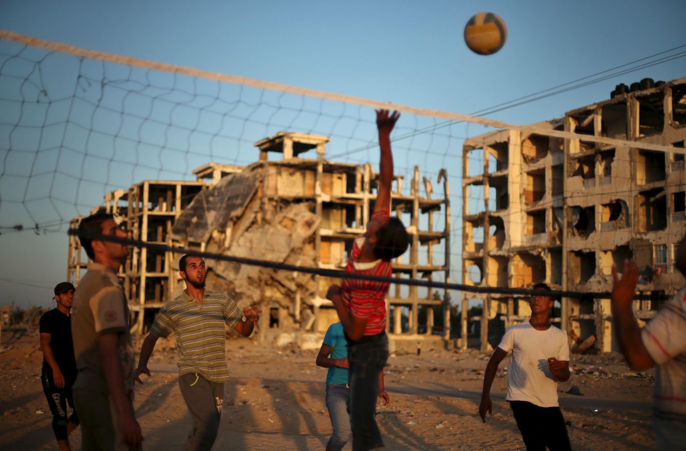 Palestinos juegan al voleibol cerca de edificios destrozados por las bombas en Beit Lahiya, Gaza (Reuters).