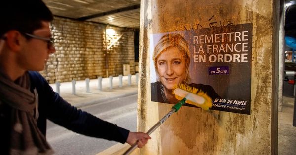 Foto: Un joven pega un póster de Le Pen en Lyon. (Reuters)