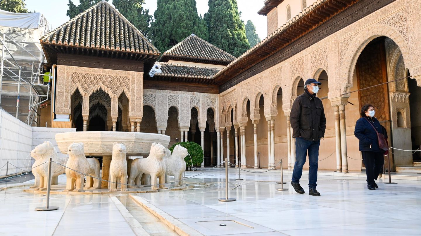 Dos visitantes, ayer, por el Patio de Leones de la Alhambra de Granada.