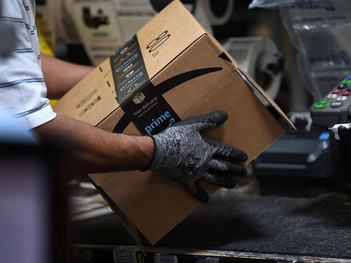 Foto: Un operario sostiene una caja con el logo de Amazon. (Reuters/Clodagh Kilcoyne)