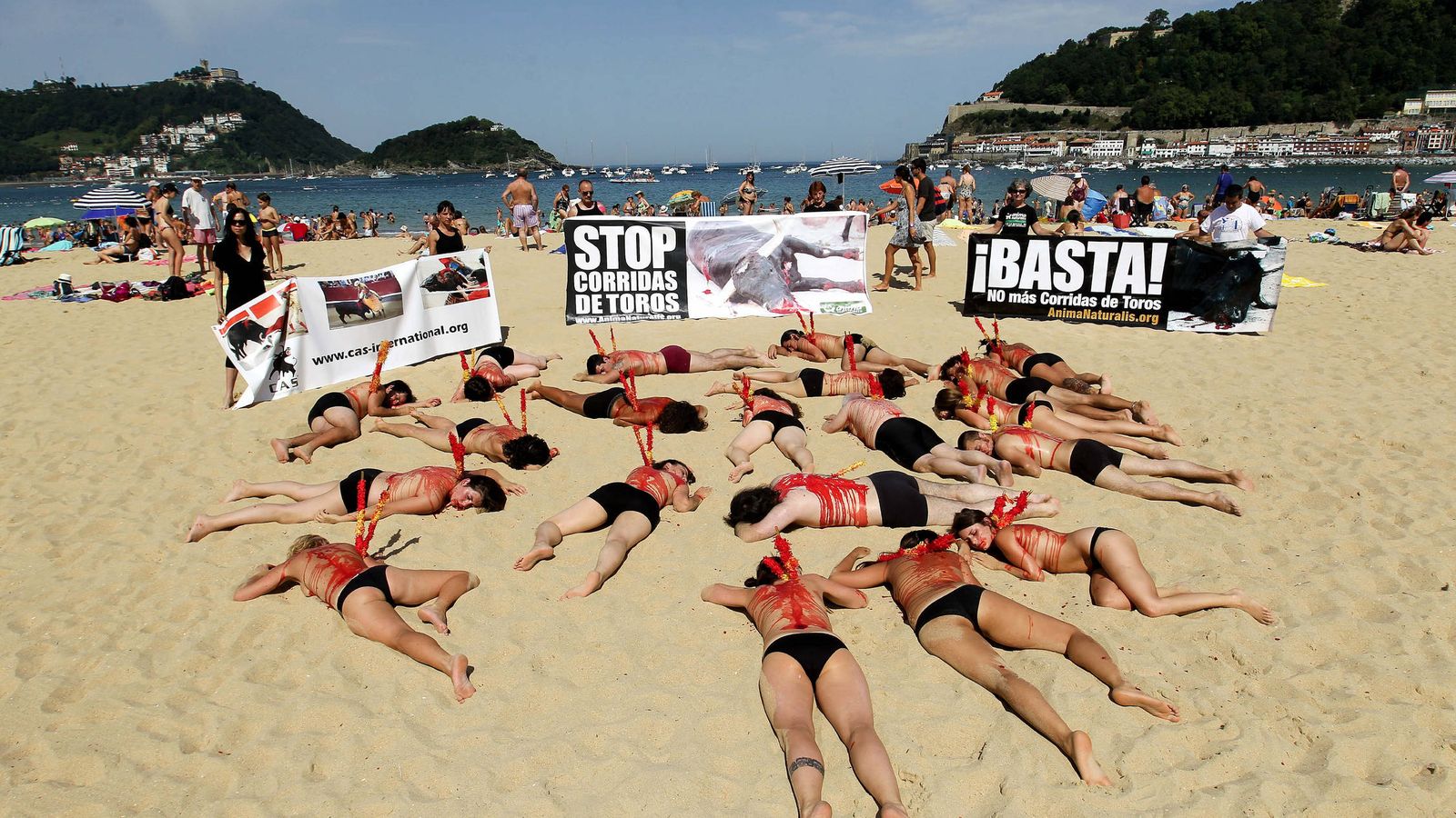 Foto: Una veintena de antitaurinos tumbados semidesnudos sobre la arena de La Concha de San Sebastián para protestar por las corridas de toros. (EFE)