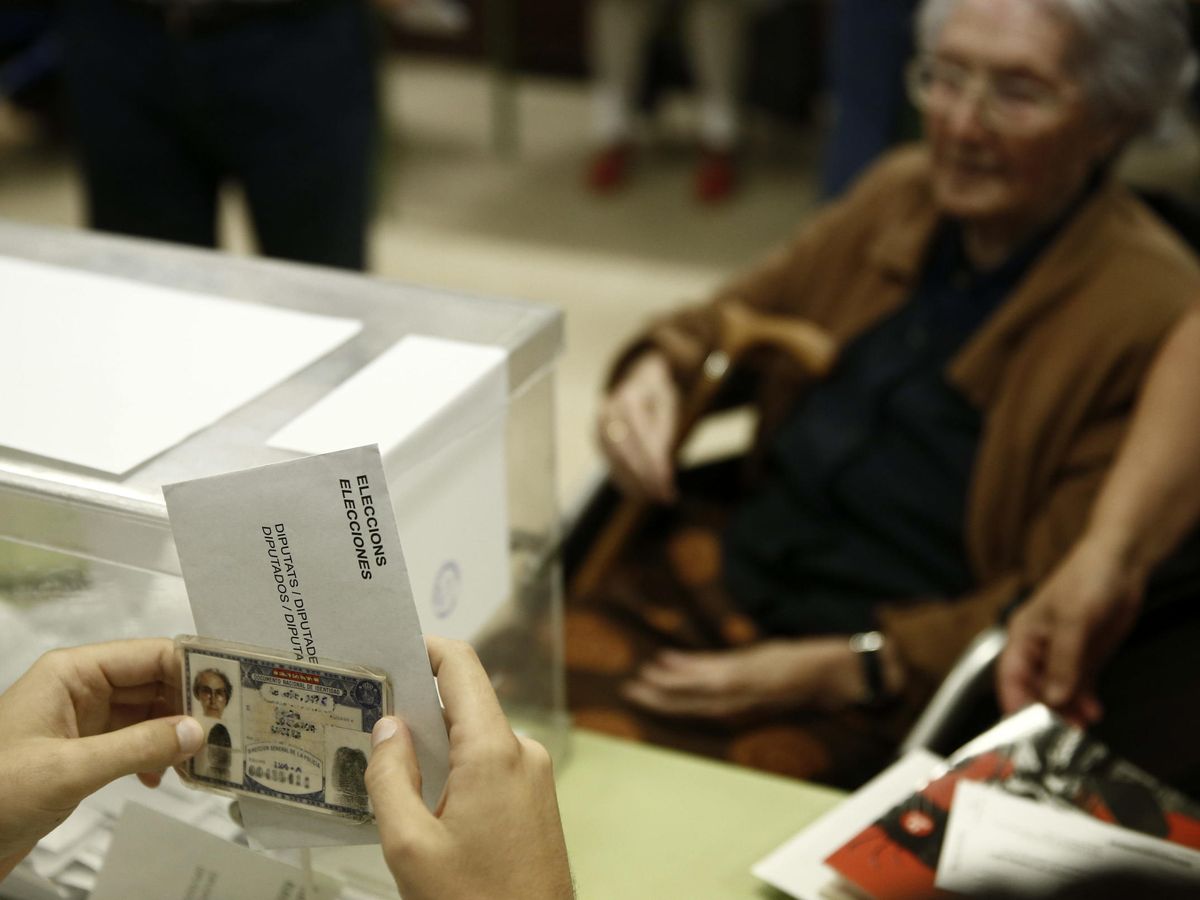 Foto: El presidente de una mesa electoral comprueba el documento nacional de identidad de una anciana. (EFE/Jesús Diges)