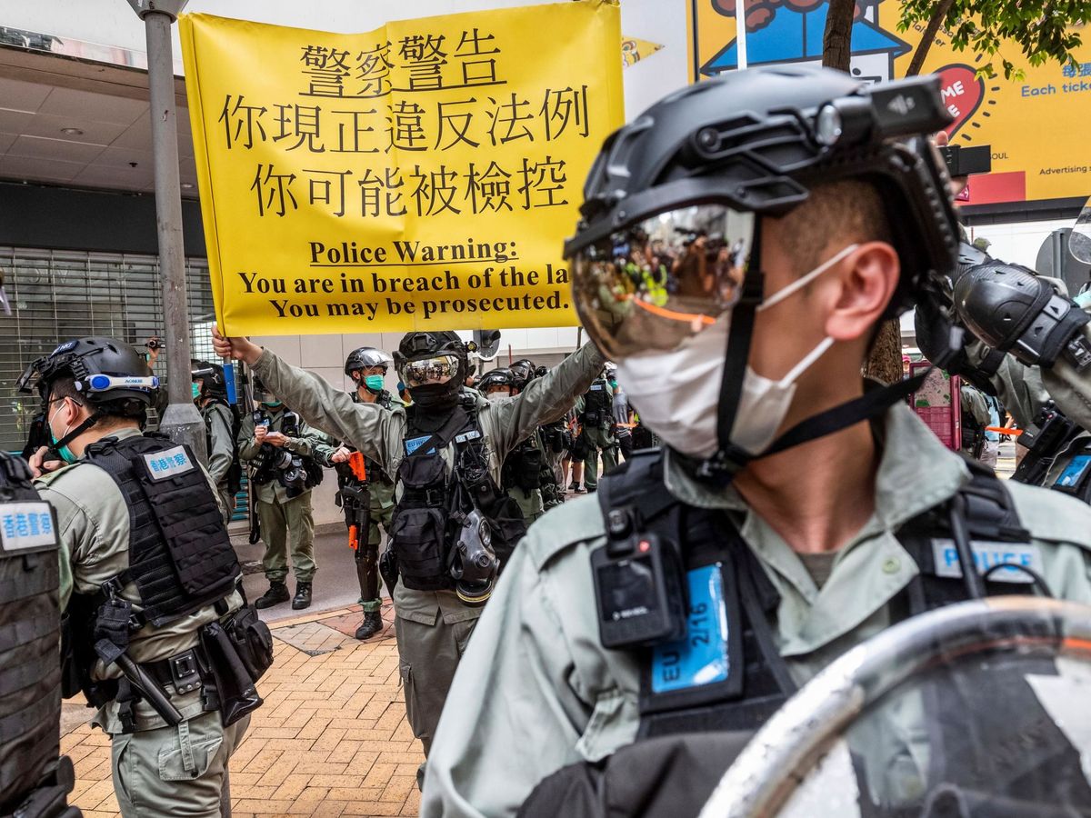Foto: Un oficial de policía muestra un cartel para avisar a los ciudadanos que podrán ser procesados si continúan manifestándose, el pasado mayo. (EFE)