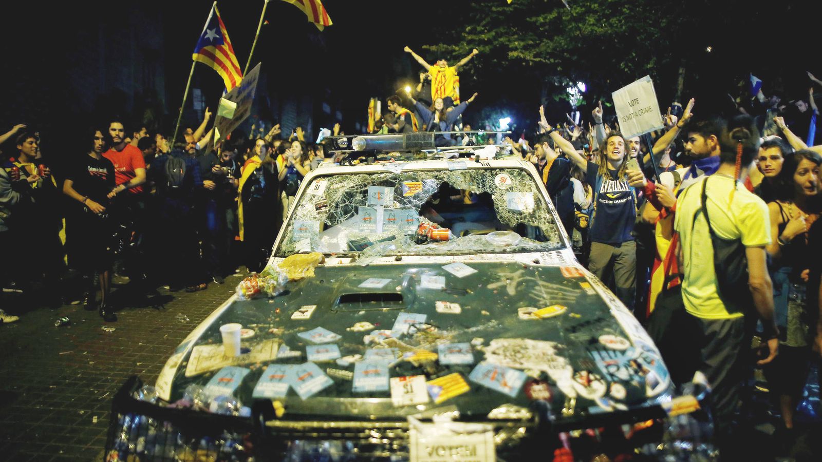 Foto: Varios manifestantes rodean un vehículo de la Guardia Civil lleno de pintadas y pegatinas. (EFE)