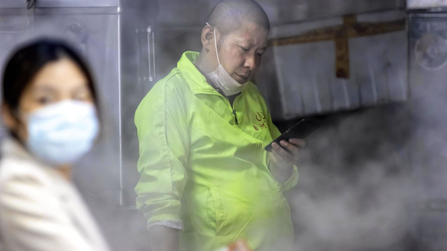 Un hombre con mascarilla prepara comida en un puesto callejero de Guangzhou, China. (Reuters)