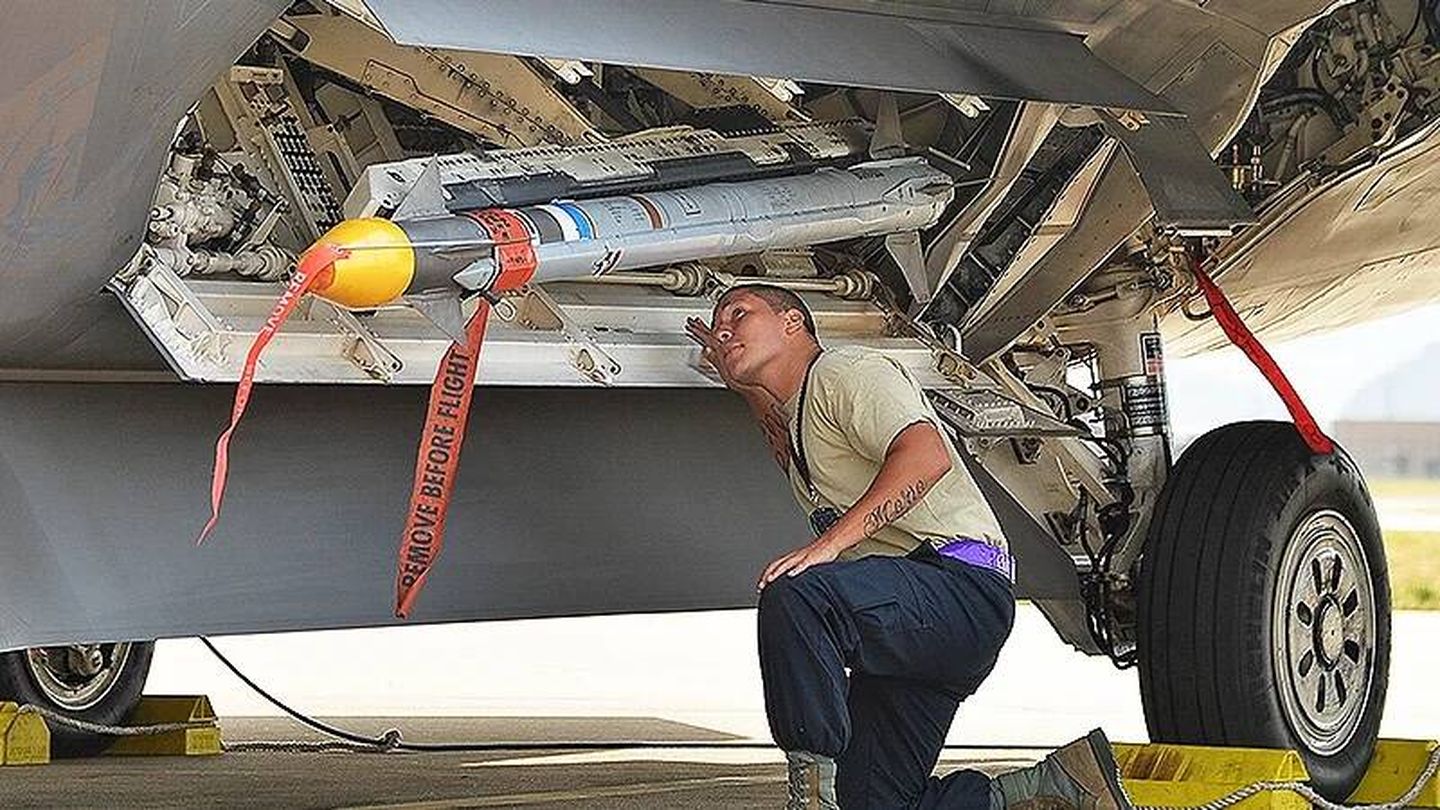 Personal de tierra cargando un misil Sidewinder en la bahía de armas de un F-22.