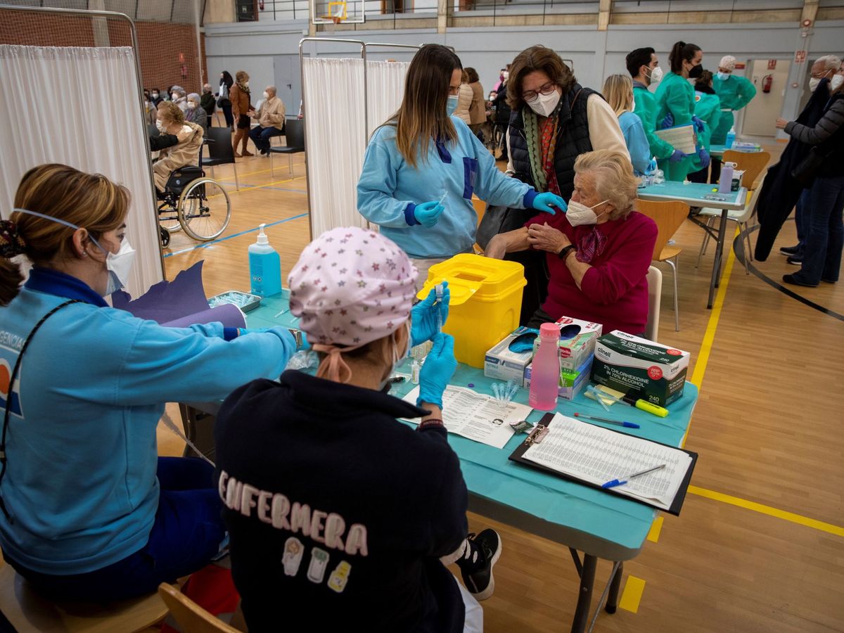 Foto: Personas mayores de 80 años son vacunadas hoy en un pabellón deportivo de la Universidad de Sevilla por sanitarios del Servicio Andaluz de Salud. (EFE)