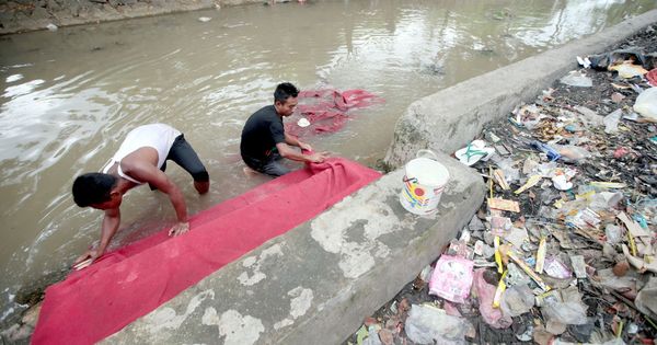 Foto: Unos hombres limpian una alfombra en un río contaminado de Indonesia. (EFE)