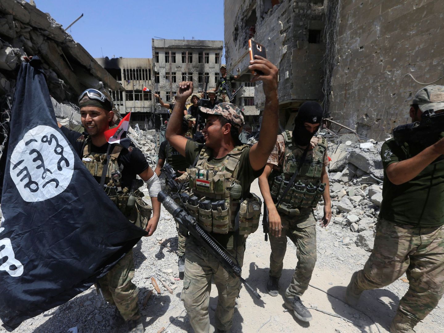 Efectivos del Ejército iraquí celebran la caída de Mosul con una bandera del Estado Islámico. (Reuters)