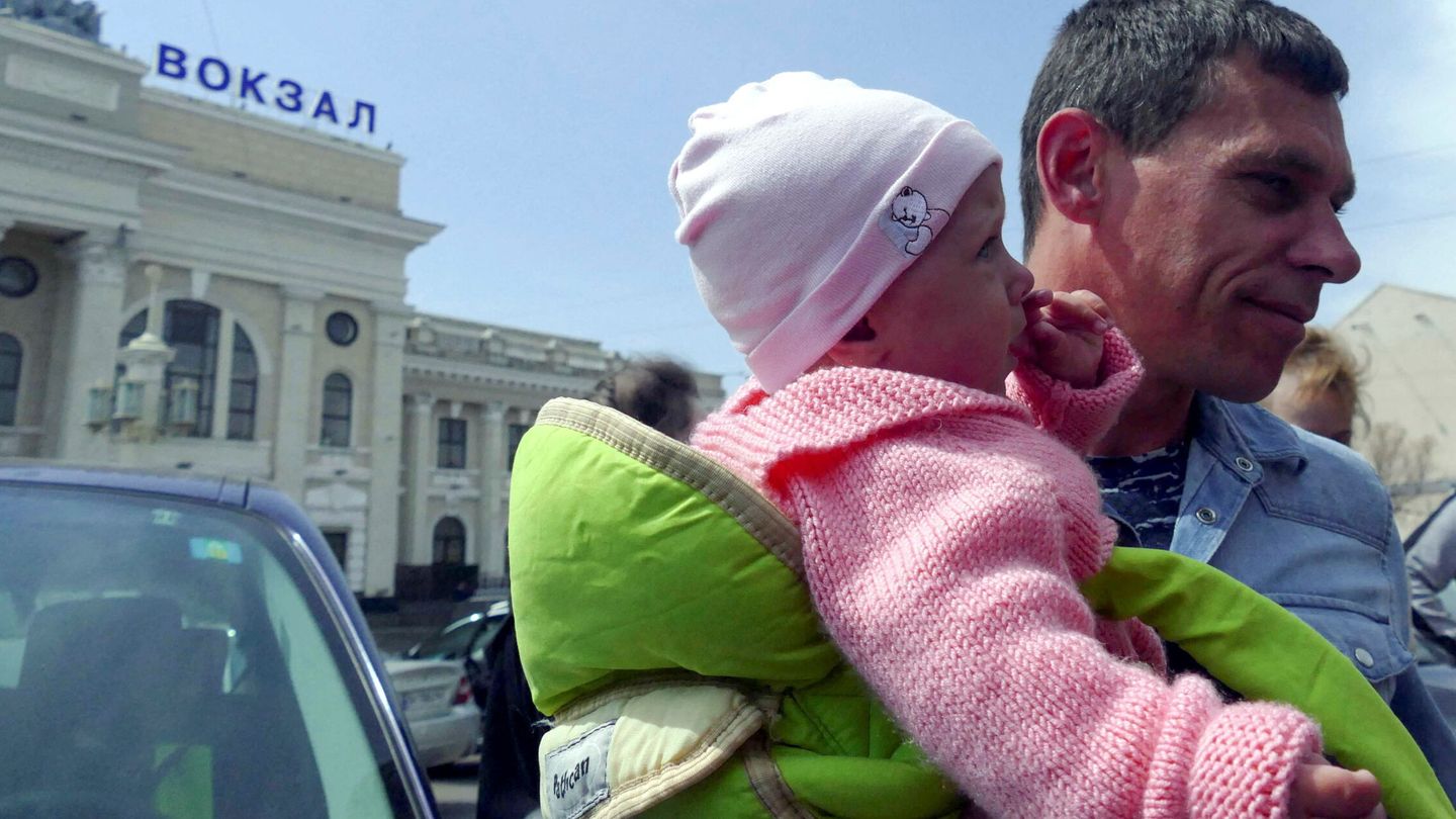 Un hombre carga a un bebé en Odesa antes de partir rumbo a Alemania. (Reuters/Igor Tkachenko)