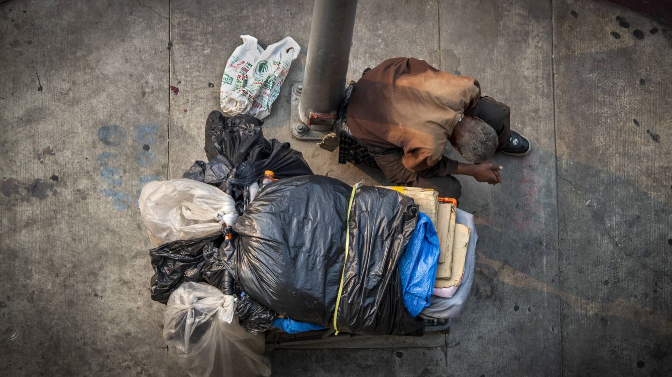 Foto: Un vagabundo descansa apoyado sobre una farola en un barrio de Los Ángeles. (Getty/Allen J. Schaben)