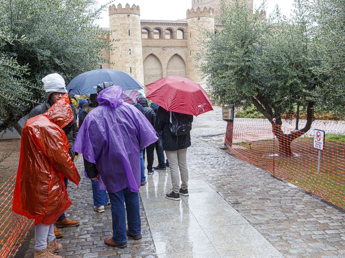 Foto: Vista de personas bajo la lluvia en Zaragoza. (EFE/Javier Belver)
