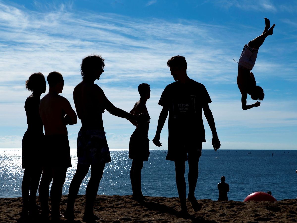 Foto: Un grupo de jóvenes realiza acrobacias en la playa de la Barceloneta (EFE)