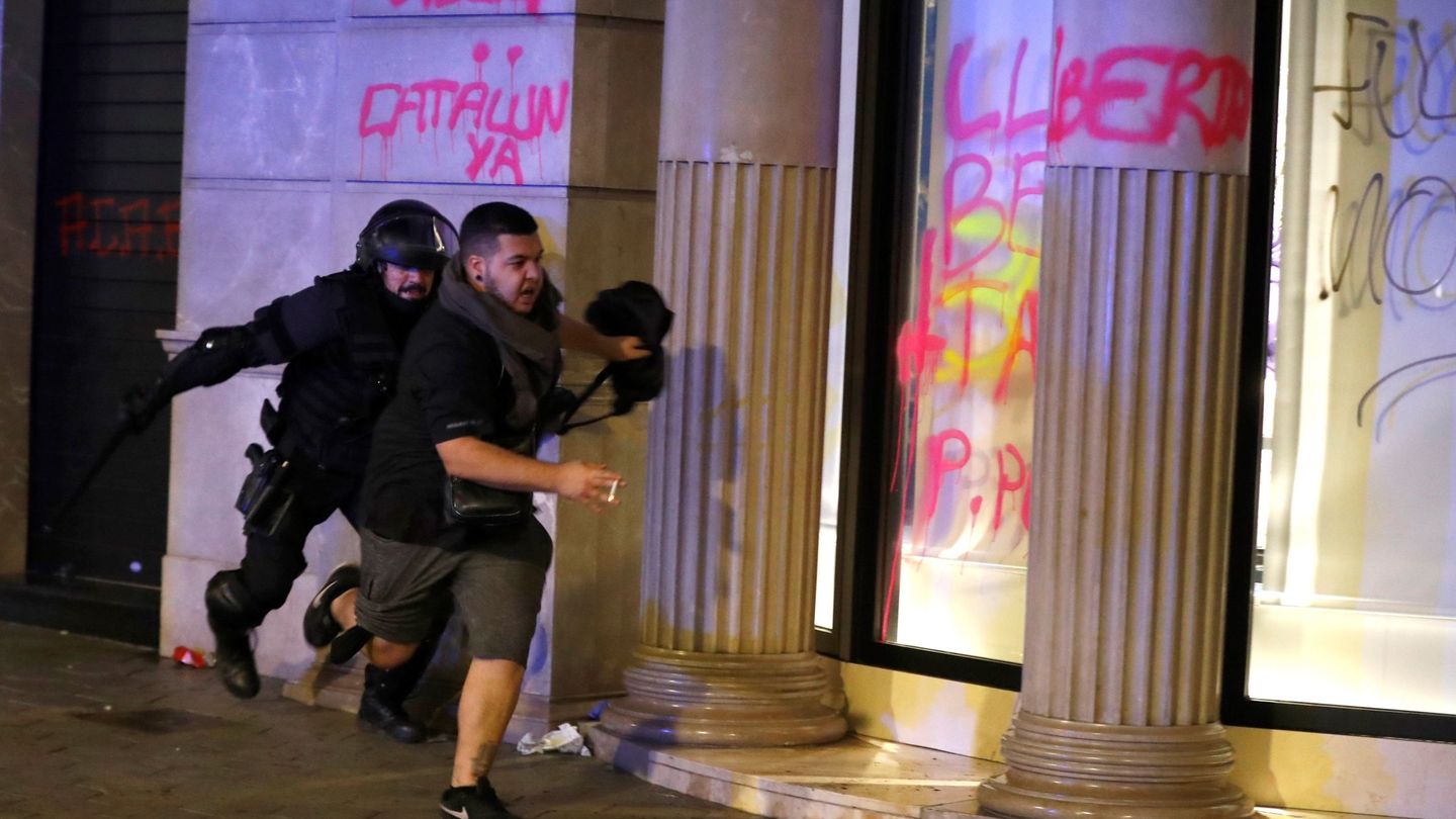 Un miembro de los Mossos d'Esquadra corre tras un manifestante. (EFE)
