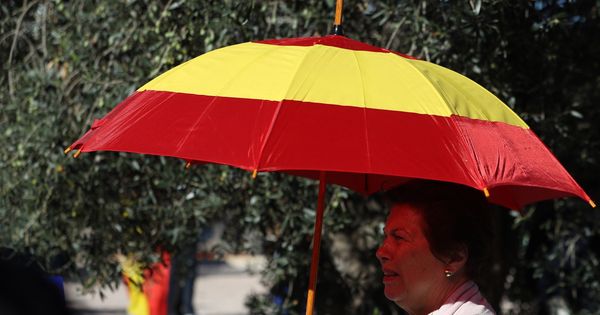 Foto:  Una mujer se protege del sol con un paraguas con la bandera de España. (EFE)