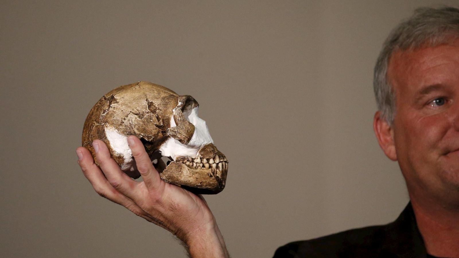 Foto: Lee Berger sostiene una réplica del cráneo del nuevo homínido