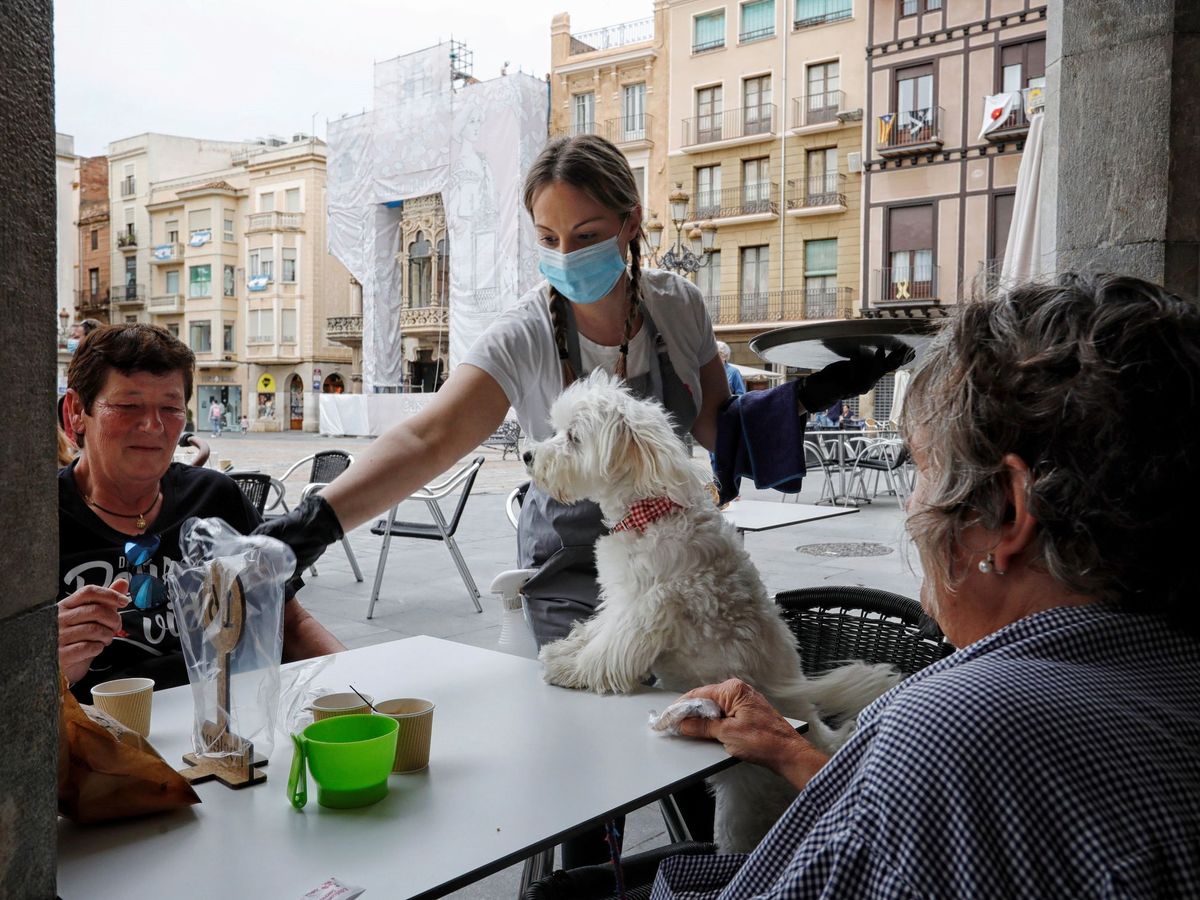 Foto: Una camarera atiende a unos clientes en la terraza de una cafetería en la Plaza del Mercadal de Reus. (EFE)