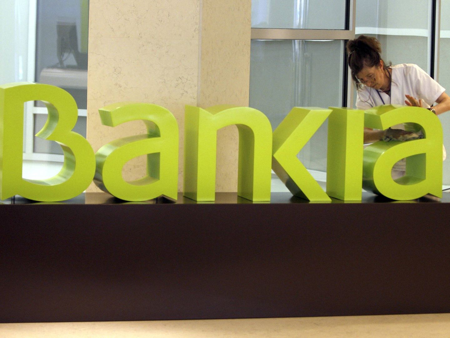 Una operaria limpia el logo de Bankia. (EFE)