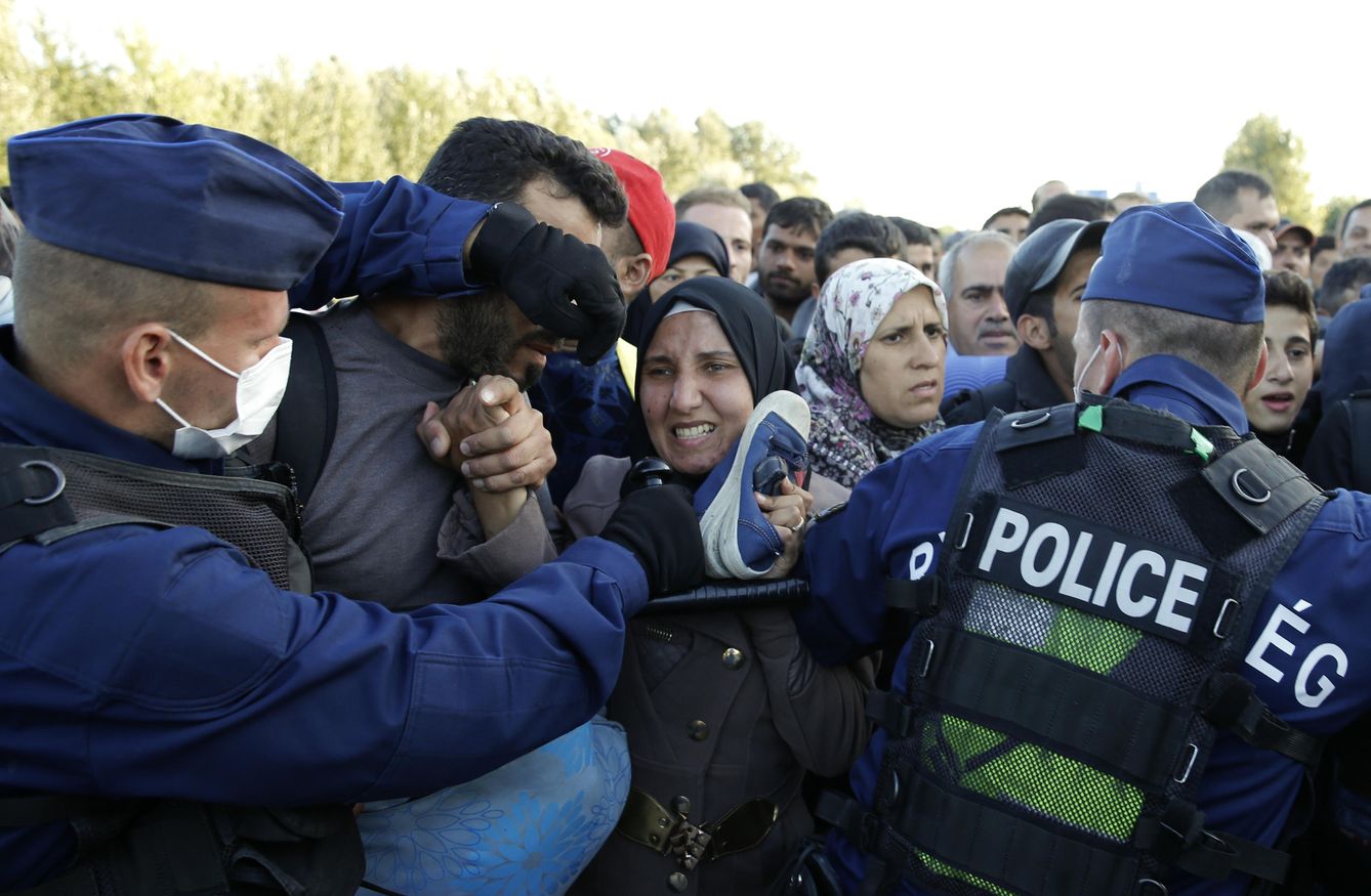 La Policía húngara forcejea con los refugiados para que pasen al puesto de control. (Reuters)