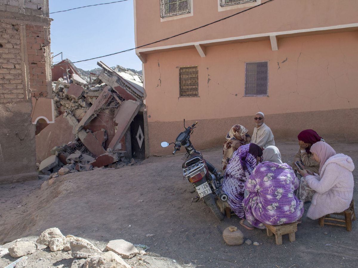 Foto: Un grupo de personas sentadas delante de un edificio en ruinas tras el terremoto en Marruecos (EFE/JALAL MORCHIDI)
