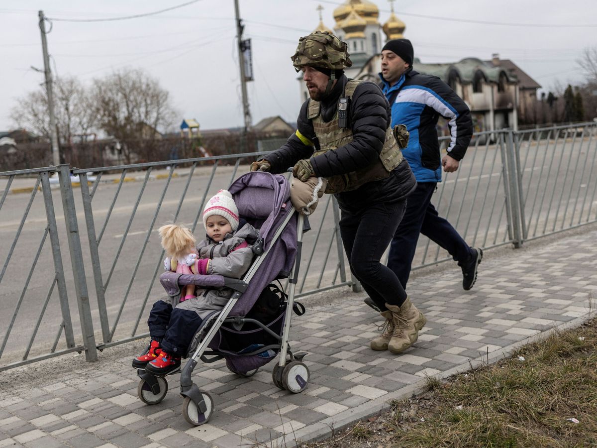 Foto: Un miembro de las fuerzas armadas ayuda a evacuar a un menor en Irpin, cerca de Kiev. (EFE/Carlos Barria)